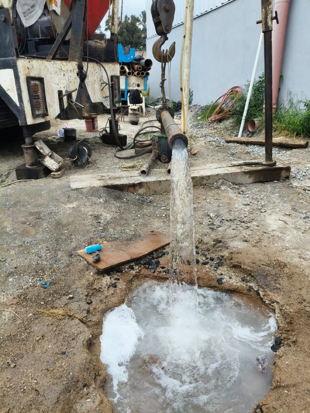 Descarga de agua durante el aforo de un pozo, junto al equipo de perforación